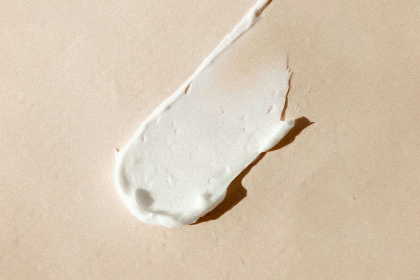 A single smear of white cream on a warm beige surface