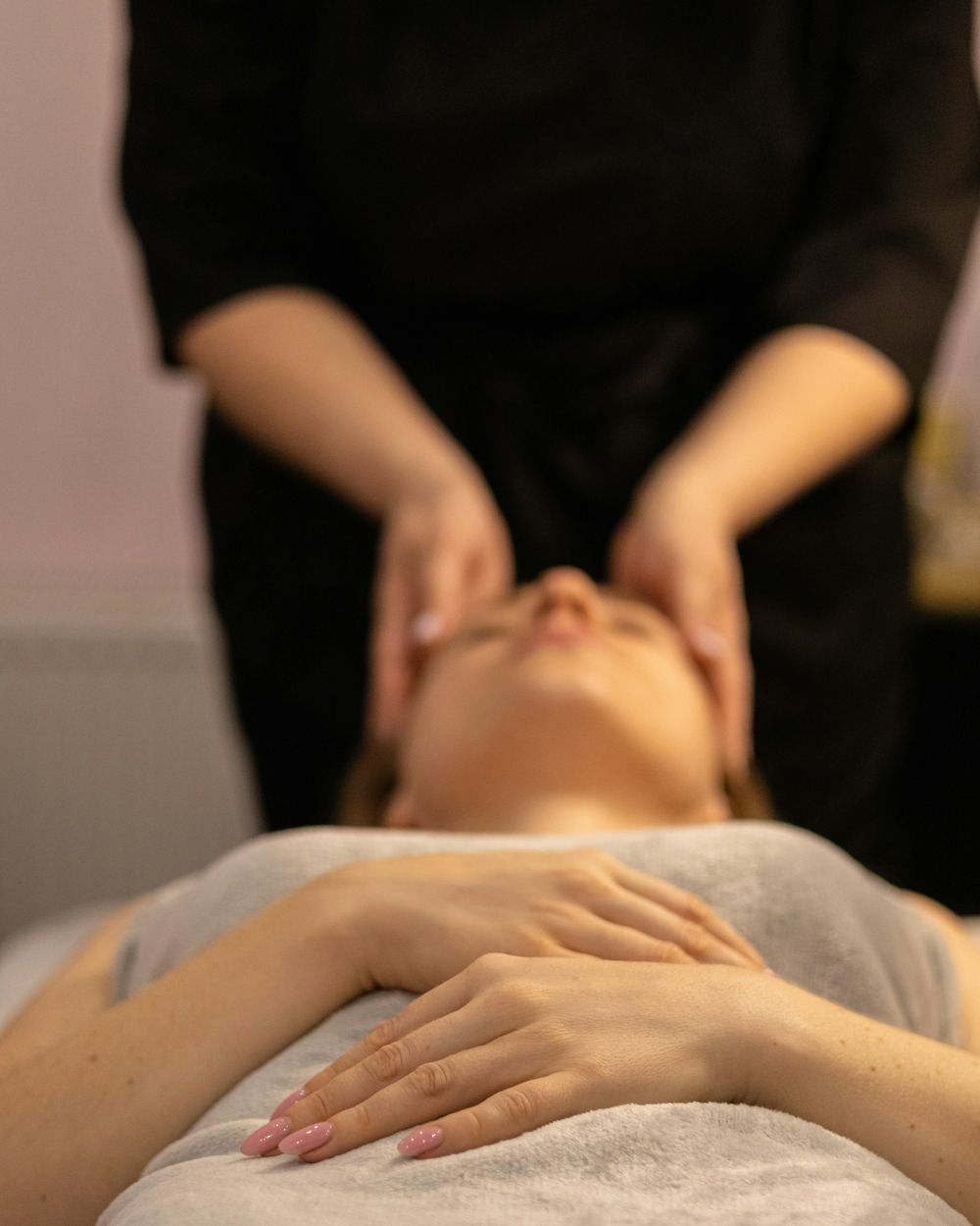 A therapist’s hands resting on a client’s face during a facial massage