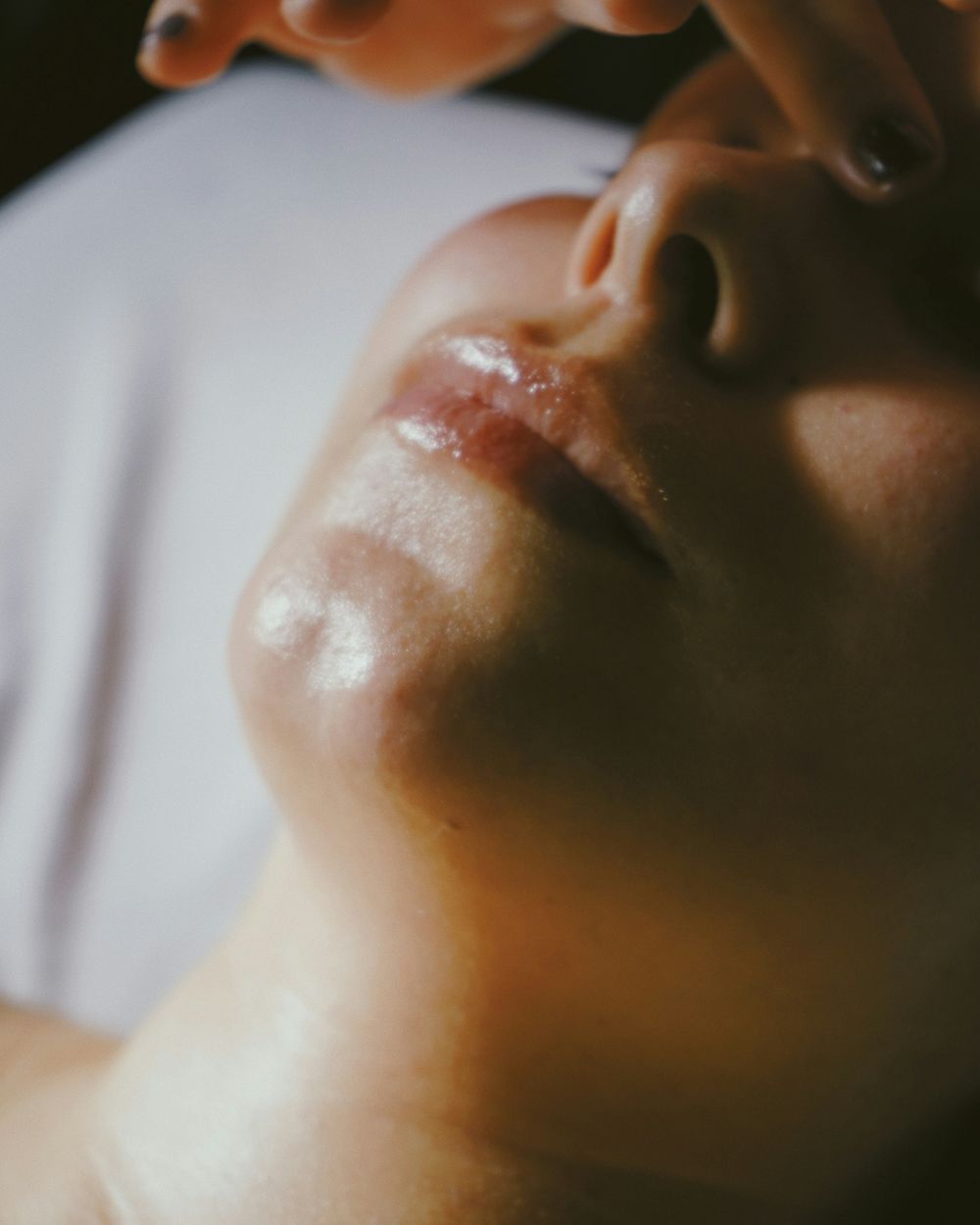 Close-up of a client with closed eyes as fingertips massage her face