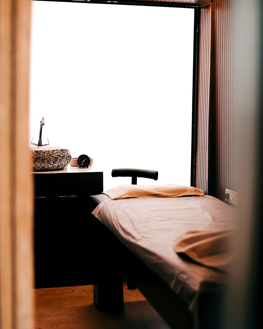 Treatment bed with folded linens beside a bright window